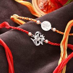 Traditional rakhis done in silver for a special relationship of siblings. Wonderful set of 2 rakhis done with 92.5 Sterling Silver one off them with Om Namah Shivay written on a round coin like dial strung to yellow and orange pleated silky multistrands and Om with a Ganesha face strung to red pleated silky strands. Both the silver dials have attractive pearls attached.    Om 925 Silver Set Of 2 Rakhis Product Category: Rakhi Threads Sub-Category : 925 Sterling Silver Rakhis Thanks for stopping Silver Bracelets With Latkans As Gift, Silver Bracelets For Festive Gift, Festive Personalized Silver Jewelry, Ganesha Face, Raksha Bandhan Gifts, Om Namah Shivay, Raksha Bandhan, Jewelry Cleaner, Silk Thread