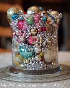 a glass vase filled with lots of different types of beads and ornaments on top of a table