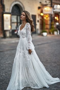 a woman is standing in the middle of an empty street wearing a long white dress