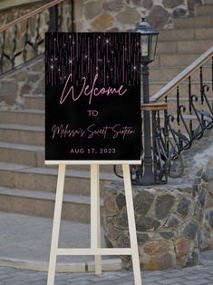 a welcome sign is standing in front of some stairs and steps with lights on it