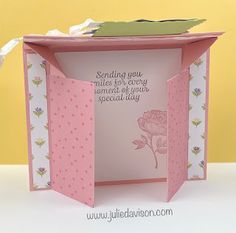 an open card box with a pink rose on the inside and some white paper around it