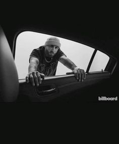 a man leaning out the window of a car with his hand on the door handle