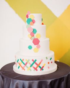 a three tiered white cake with multicolored dots on the top and bottom