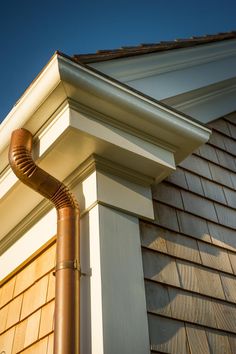 a brown gutter hose is attached to the side of a house's roof