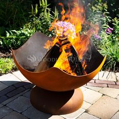 an outdoor fire pit with flames coming out of the top and flowers in the middle