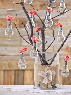 a vase filled with lots of light bulbs hanging from a twig and tree branch