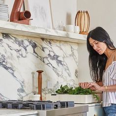 a woman standing in front of a stove preparing food on top of a cutting board