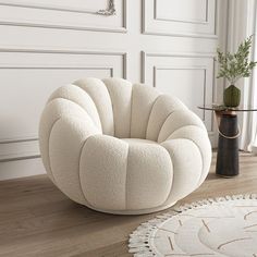 a white chair sitting on top of a wooden floor next to a vase and rug