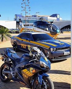 two police motorcycles parked next to each other on a brick road with a helicopter in the background