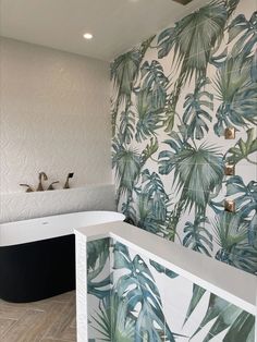 a bathroom with tropical wallpaper and white bathtub