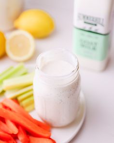 carrots and celery sticks on a plate next to a jar of dressing