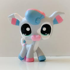 a little pony with big eyes and pink ears standing next to a white wall in front of it