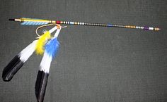 three feathers are attached to the handle of a fishing pole on a gray surface with black and white stripes