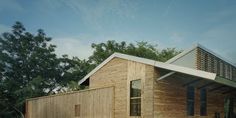 a small wooden house sitting on top of a grass covered field next to trees and bushes