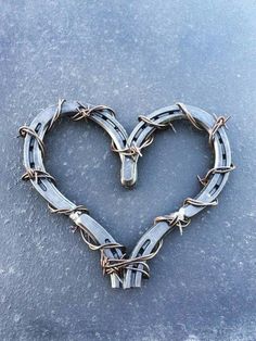 a heart shaped barbed wire on top of a gray surface with the word love written in it