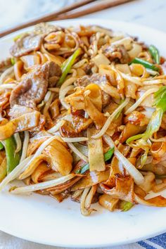 a white plate topped with noodles and meat