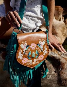 Embrace the spirit of nature with our Bohemian Hummingbird Handbag. Crafted from high-quality leather, this boho chic bag features intricate hummingbird and floral embroidery, turquoise embellishments, and playful fringe. Perfect for festivals, beach days, or casual outings, this bag combines functionality with style. The adjustable strap ensures a comfortable fit, while the spacious interior with multiple pockets keeps your essentials organized. Elevate your boho style with this unique, handmad Double Fringe, Boho Chic Bags, Hand Painted Leather, Painting Leather, Dark Tan, Saddle Bag, Turquoise Stone, High Quality Leather, Flower Design