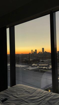 a bedroom with a view of the city at sunset