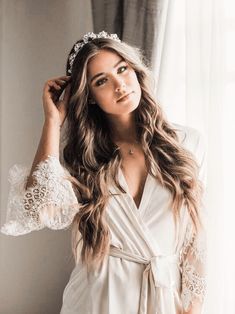 a beautiful woman wearing a white robe standing in front of a window