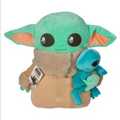 the child yoda plush toy is holding a blue stuffed animal