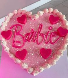 a heart shaped cake with pink frosting and hearts on it's side that says barbie