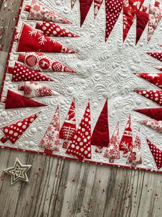 a red and white quilted table runner with christmas trees on it, surrounded by starbursts