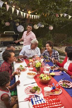 a group of people sitting around a table with plates and bowls of food on it