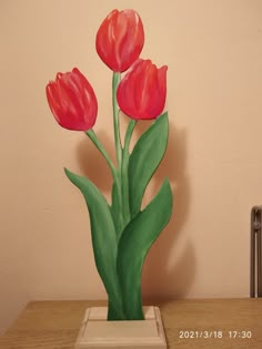 a painting of three red tulips in a white vase on a wooden table