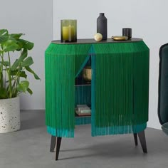 a green cabinet sitting next to a potted plant and a black chair in front of it