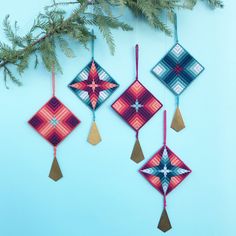 three ornaments hanging from a tree branch on a blue background with pine branches and needles