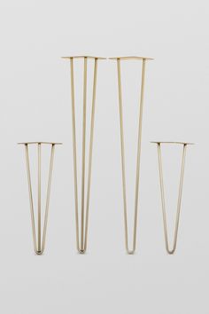 three gold - plated metal candlesticks are lined up against a white background