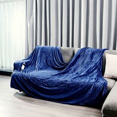 a couch covered in a blue blanket next to a window