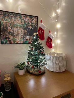 a small christmas tree with stockings hanging from it's sides on a wooden table