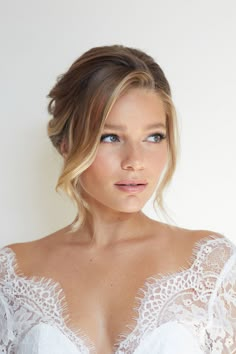 a woman in a white dress with blue eyes and blonde hair is posing for the camera