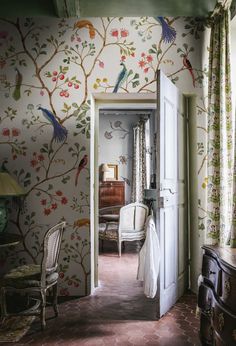 an open door leading to a bedroom with floral wallpaper and bird designs on the walls