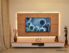 a flat screen tv mounted to a wall in a living room next to vases