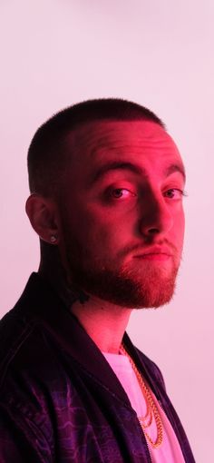 a man with piercings on his head looking off to the side in front of a white background