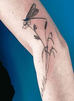 a woman's arm with a flower and dragonfly tattoo on the left side