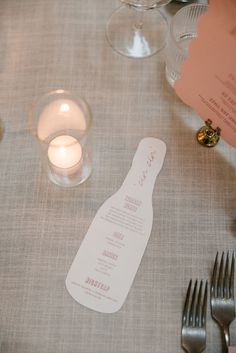 the table is set with silverware, candles and menus for dinner or reception