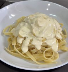 a white plate topped with pasta covered in gravy on top of a table