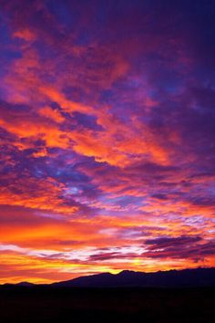 the sky is purple and orange as the sun sets in the distance with mountains in the background