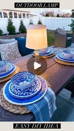 an outdoor table with blue and white plates on it, next to a lamp that reads easy diy idea