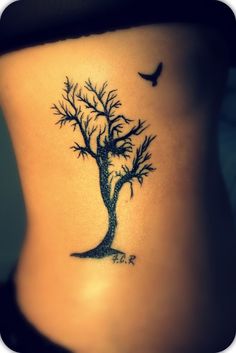 a woman's stomach with a tree and bird tattoo on her lower back side