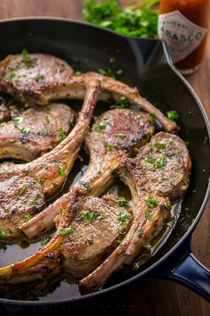 steaks in a skillet with garnishes and sauce on the side