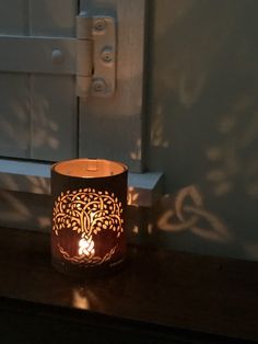 a lit candle sitting on top of a wooden table next to a white door handle