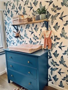 a baby's crib in the corner of a room with blue drawers and wallpaper