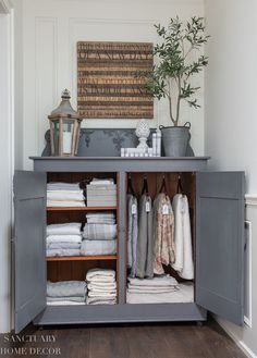 an open cabinet with towels and blankets on it in a room that has wood floors