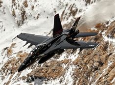 a fighter jet flying through the air over snow covered mountains