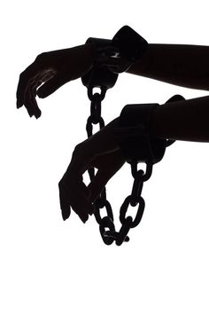 the silhouette of two hands holding chains in front of a white sky with no clouds