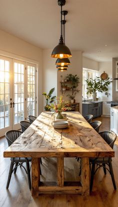 a large wooden table sitting in the middle of a living room next to a kitchen